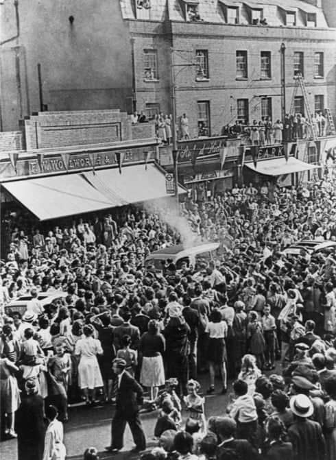 Every vantage point in the High Street is taken as the torch runners are engulfed by the crowd during the transfer of the flame. © Dorking Museum